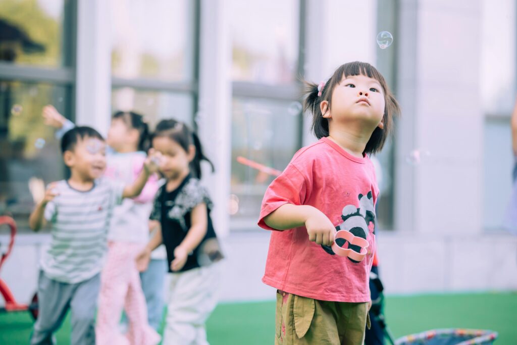 pexels photo 18830331 18830331 1 Group of children joyfully playing with bubbles in a sunny outdoor setting.